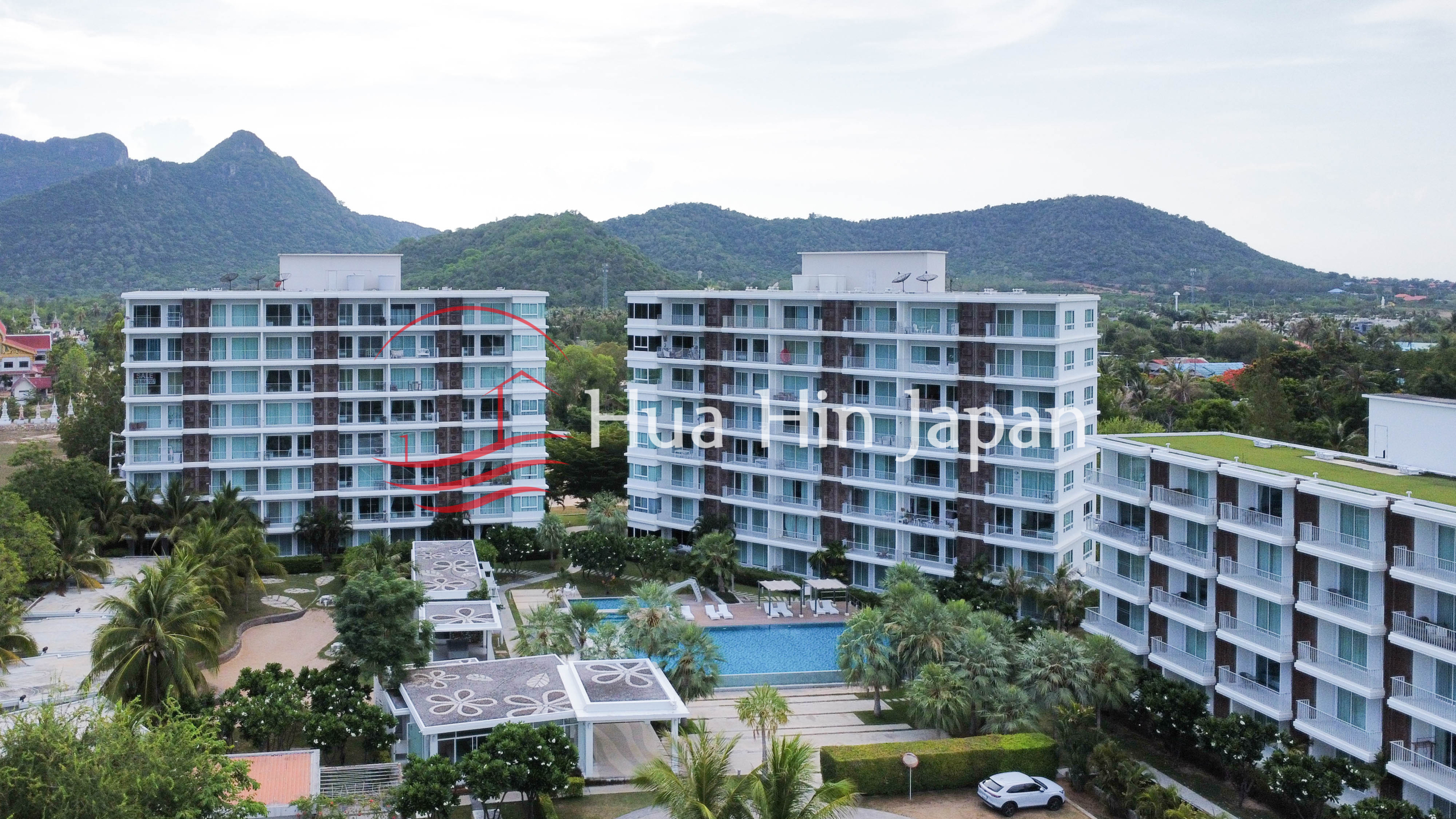 Modern luxury condominium complex surrounded by tropical gardens with mountains in the background