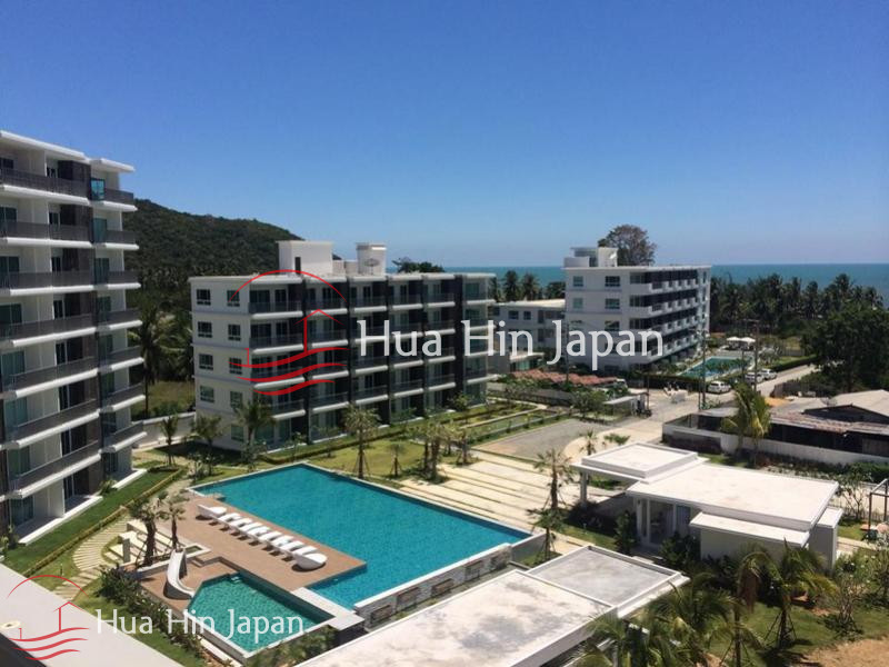 Aerial view of a modern seaside residential complex with swimming pools, landscaped grounds, and ocean views