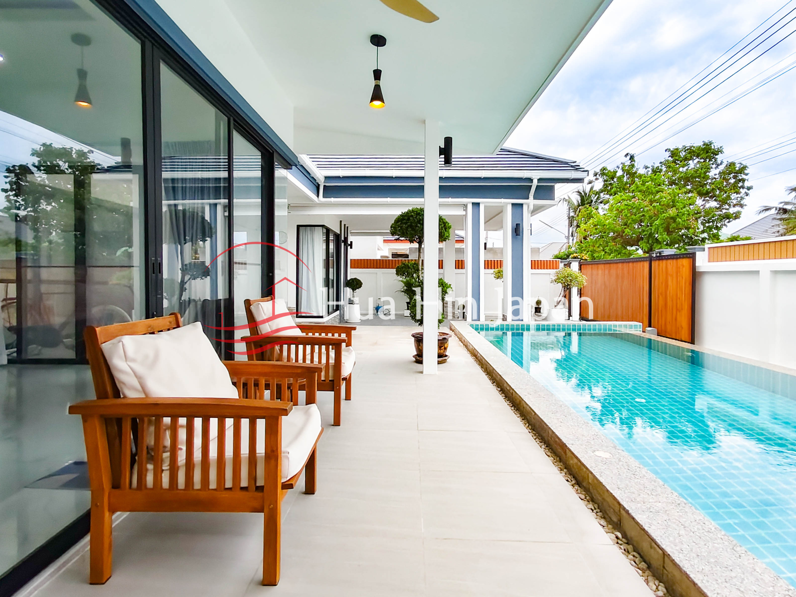 Modern villa patio with swimming pool, glass doors, outdoor seating, and landscaped garden