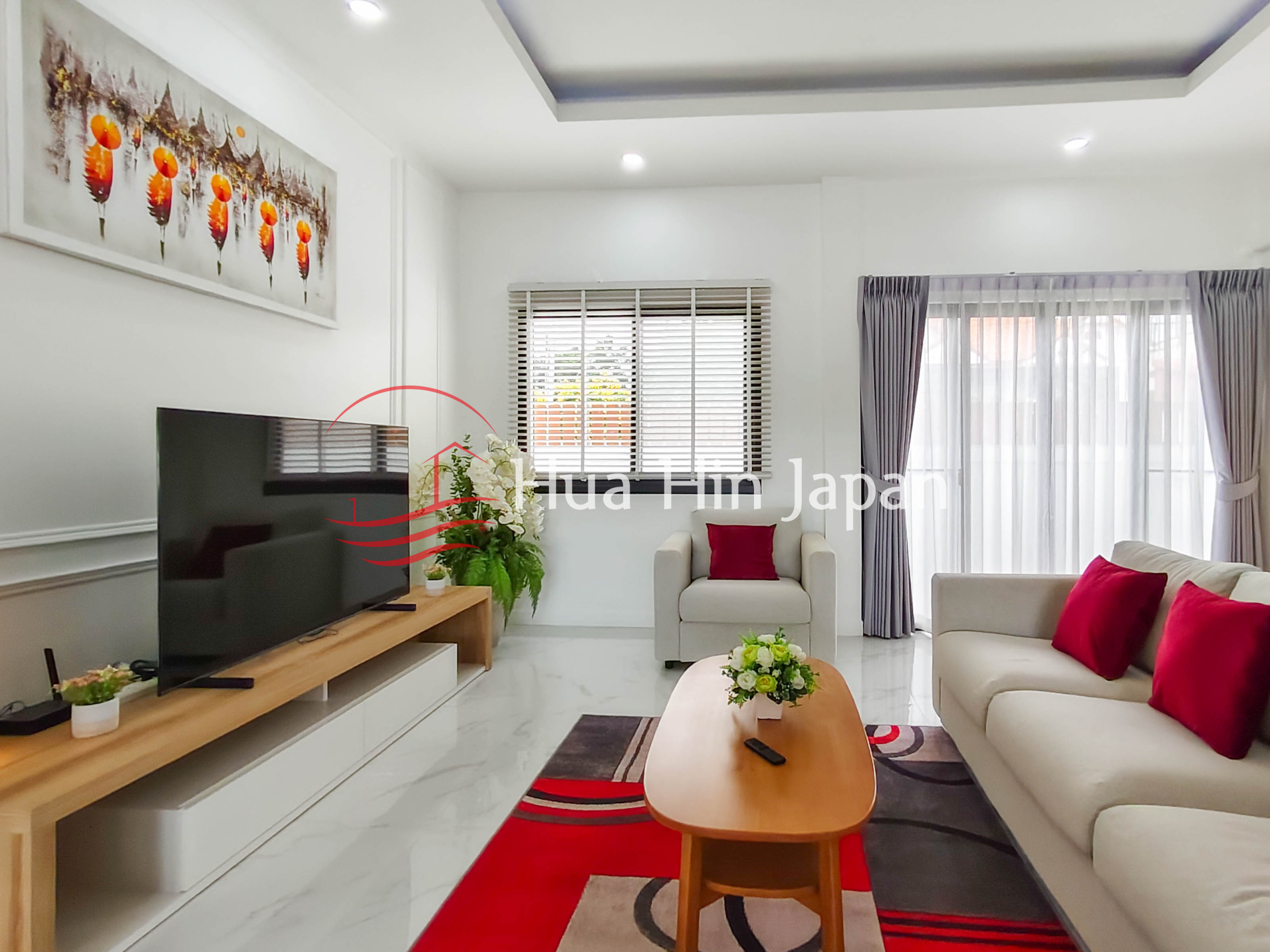 Modern living room with sofa, coffee table, indoor plant, curtains, and large window