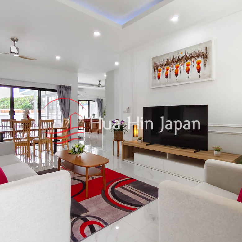 Modern open-plan living and dining area with sofa, dining table, and large windows