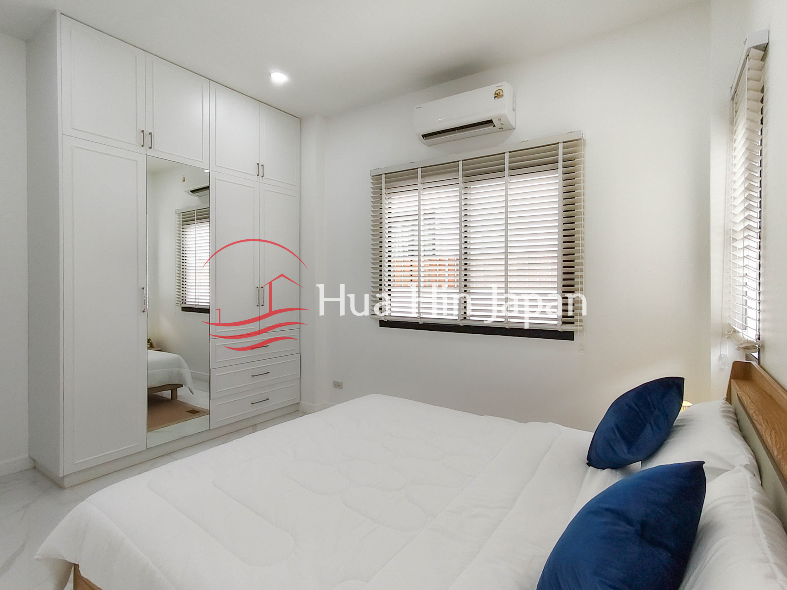 Modern bedroom with large window blinds, bed, air conditioning, and white walls