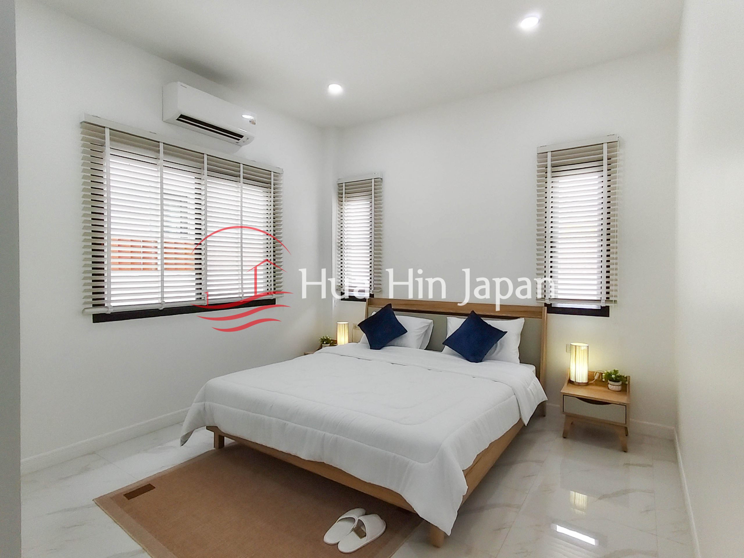 Bright bedroom with large window blinds, white walls, bed, and recessed ceiling lights