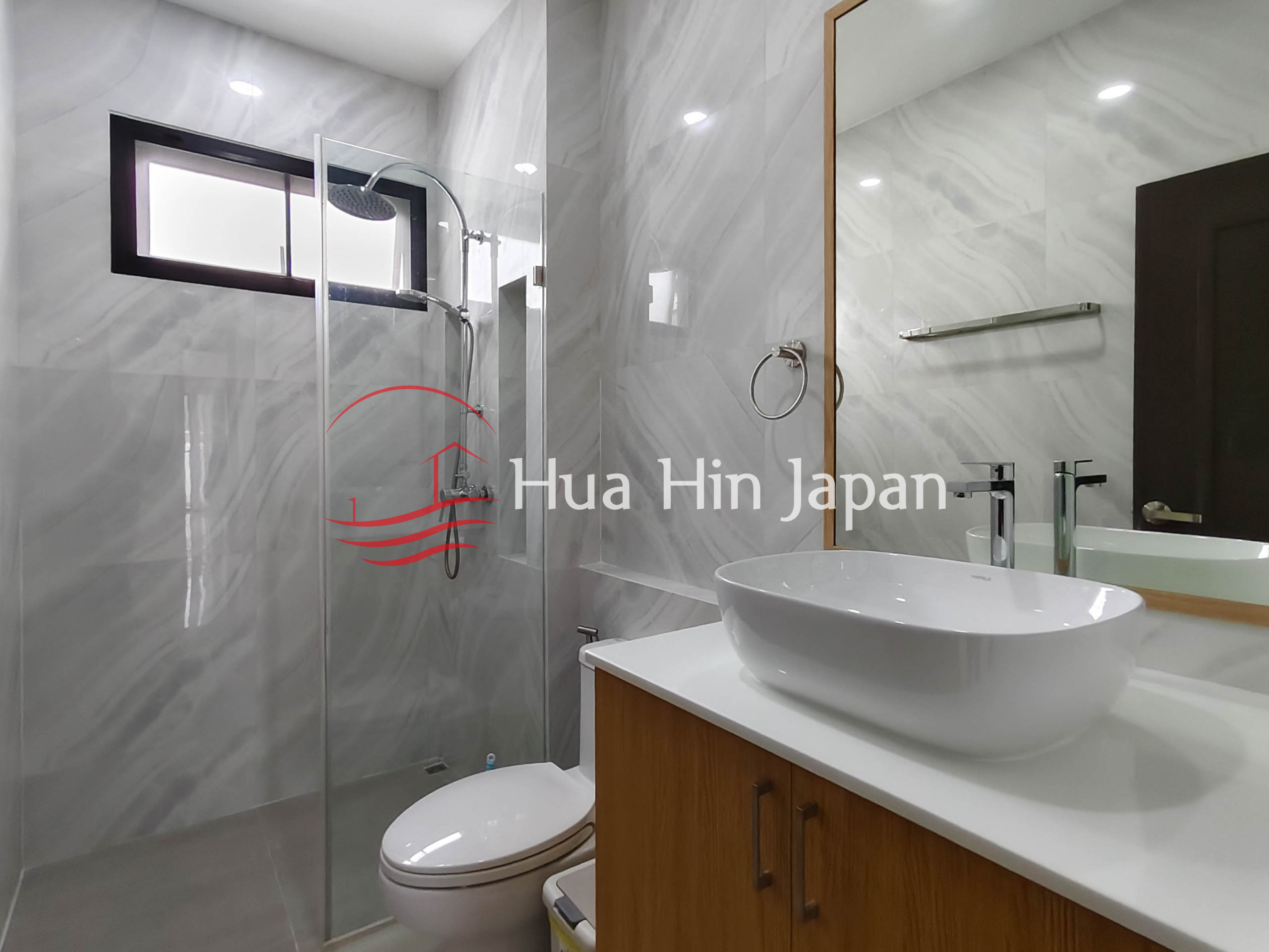 Modern bathroom with marble-look tiled walls, bathtub, and window