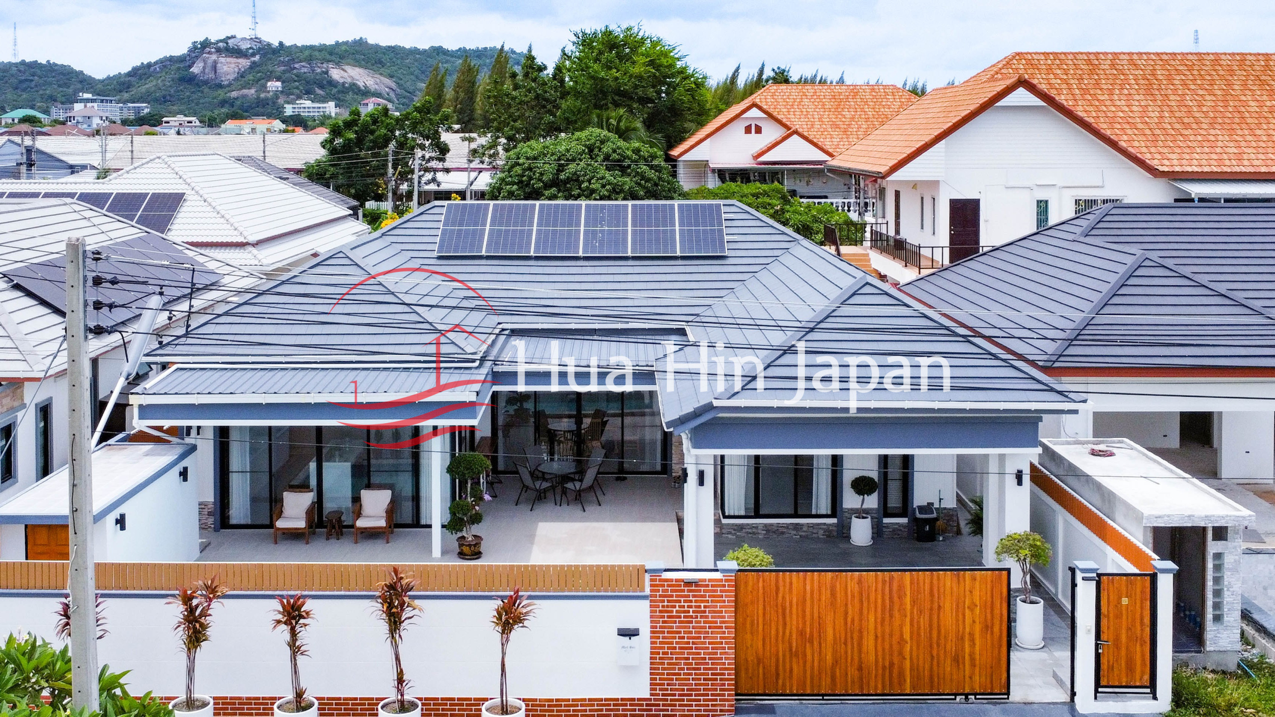 Villa rooftop with solar panels, neighboring houses, and green trees