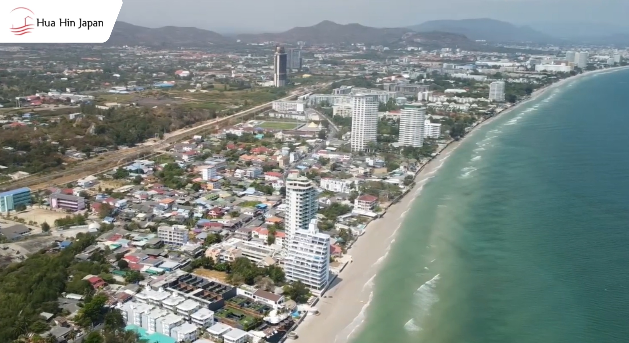 Aerial view of Hua Hin beach at sunset, showing turquoise water, sandy shores, and beachfront resorts near Khao Takiab hill in Thailand.